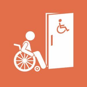 grafika: osoba na wózku przed toaletą dla osób z niepełnosprawnościami 